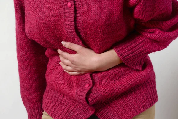 portre fotoğraf. bir kadının midesinde bir ağrı vardır ve onun ellerini tutar. Kadın tıp kavramı. Sindirim sorunları, kadın hastalıkları gebelik, adet kanamaları, mide