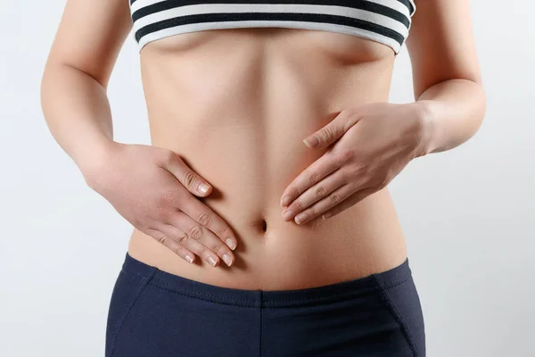 erken gebelik, doğru beslenme, kadın sağlığı kavramı. ince güzel göbek ve göbek bir kadının yakın çekim fotoğraf. Beline ellerini iki avuç dokunur. Beyaz backgr
