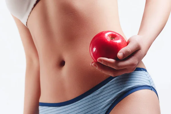 クローズ アップ。ほっそりスリムな腰腹若い女性少女。ジューシーな赤いリンゴを保持します。白い背景に分離 — ストック写真