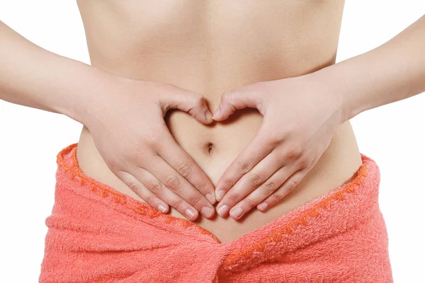 Ein junges Mädchen zeigt ihren Händen das Symbol des Herzens auf ihrem Bauch. isoliert auf weiß. Konzept der frühen Schwangerschaft, die Gesundheit der Frauen. — Stockfoto