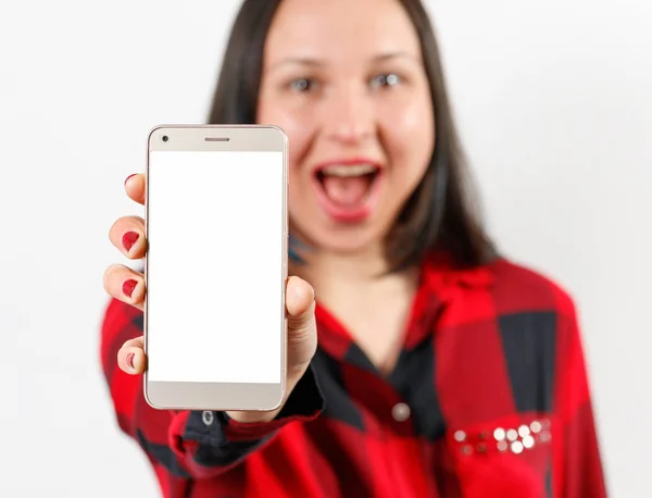 Молодая девушка в красно-черной рубашке держит смартфон с чистым белым экраном вертикально перед ней — стоковое фото