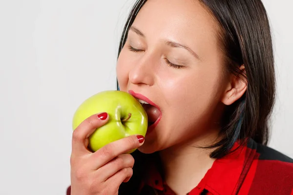 Mulher bonita alegre comendo maçã sobre fundo branco — Fotografia de Stock