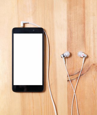 Müzik dinle. siyah kasave boş beyaz ekran lı dikey akıllı telefon ve ahşap yüzeyde kulaklı kulaklıklar