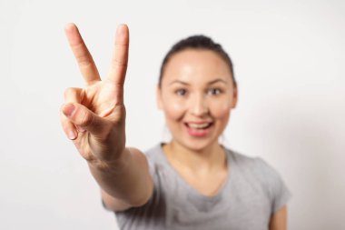 Güzel genç mutlu gülümseyen kız victopy eliyle şarkı gösteren. Barış kavramı. Jestlerin işareti. Tamam
