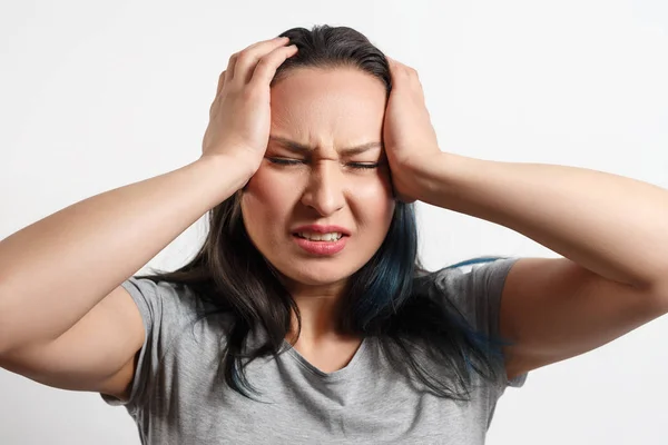 genç bir kız iki eliyle başını kapmak ve şiddetli bir baş ağrısı tasvir. Beyaz arka planda