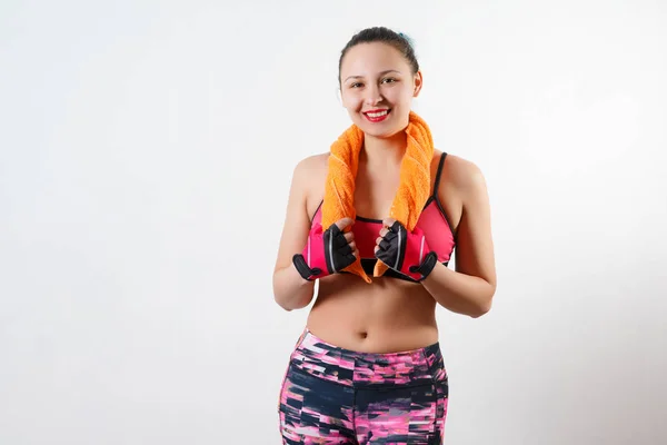 Schöne Mädchen in Sportkleidung hält ein Handtuch mit beiden Händen um den Hals. isoliert auf weiß — Stockfoto