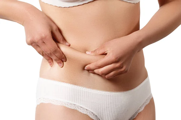 Žena v bílém spodním prádle si rukou bere extra tuk po stranách břicha. izolovat na bílém pozadí — Stock fotografie