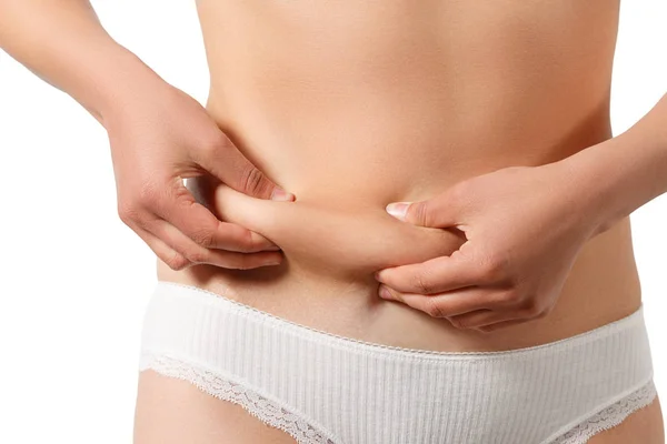Woman in white underwear takes extra fat on the sides of her stomach with her hand. isolate on white background — Stock Photo, Image