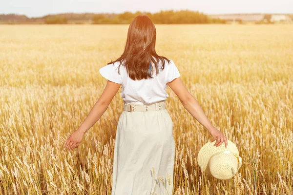 Mujer feliz con un vestido volador y un sombrero en un campo de trigo. Libertad, concepto de alegría . —  Fotos de Stock