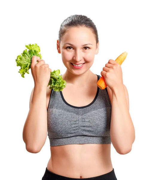 Güzel vücutlu ince bir kadın elinde sebze, havuç ve marul tutuyor. Beyaz arkaplanda izole.