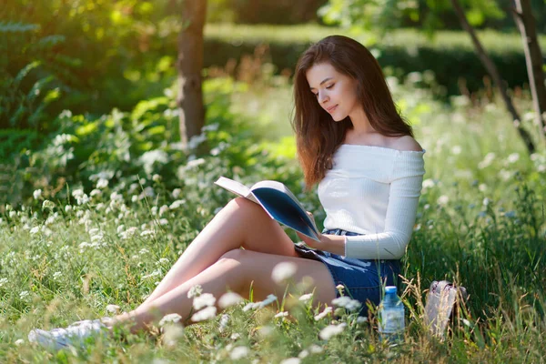 美丽的小女孩在室外的一个夏季公园里看书 — 图库照片