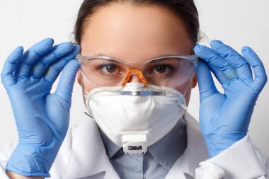 Koruyucu eldivenli, gözlüklü ve solunum maskeli bir kadın doktor portresi. beyaz arkaplanda