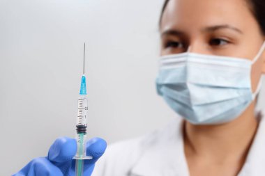 Eldivenli bir doktor ve şırıngalı koruyucu bir maske. Coronavirus covid-19 'a karşı aşı