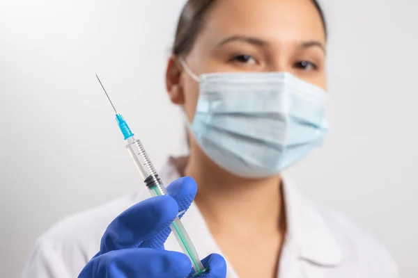 doctor in gloves and a protective mask with a syringe. vaccination against coronavirus covid-19