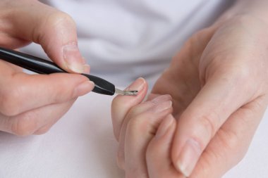 Ev manikürü. Salgın ve karantina sırasında çivilerin kendi kendine tedavisi. Özel bir araçla tırnak içi temizleme.