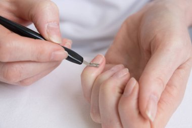 Ev manikürü. Salgın ve karantina sırasında çivilerin kendi kendine tedavisi. Özel bir araçla tırnak içi temizleme.