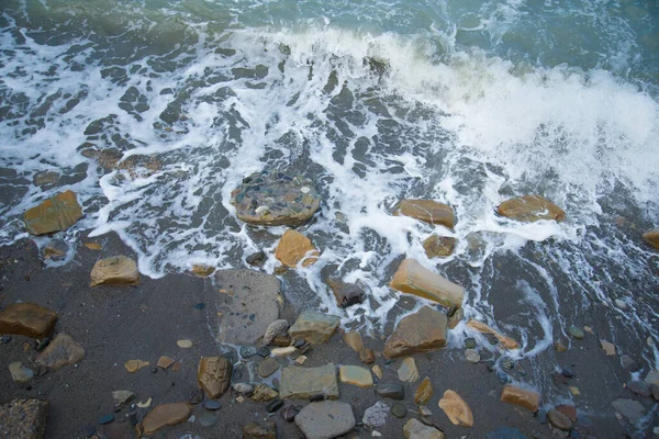 Top view of the sea wave and rocks. The water forms a whimsical pattern. Background