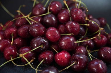 Siyah arka planda kırmızı taze kirazlar. Bir damla su. Kapatın. Tazelik kavramı.