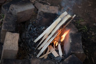 Ateş için bir yer, tuğlalarla çevrili. Yangını başlatma süreci. Küçük parçalar yanmaya başlar..
