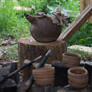 Dumanı tüten bir çaydanlık ve çay fincanı. Kil tencerede ateşte çay hazırlamak. Kamp gezisi, yolculuk..