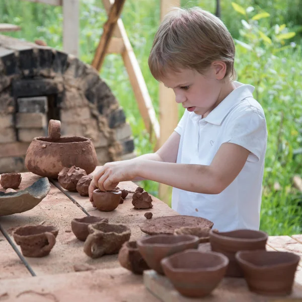 The child makes dishes and various figures from clay. Pottery skills. Hobbies and interests. Childrens education, expanding horizons. — Stock Photo, Image