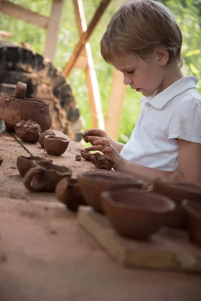 The child makes dishes and various figures from clay. Pottery skills. Hobbies and interests. Childrens education, expanding horizons. — Stock Photo, Image