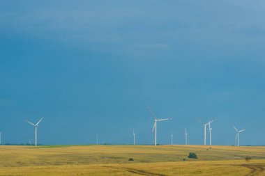 Mavi gökyüzü arka planındaki rüzgar santrallerinin alanı. Metin için boşluk.