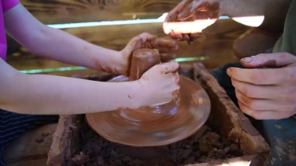 De Pottenbakker leert het kind aan het Pottenbakkerswiel te werken. Handen van mensen in close-up. Werken met klei, handgemaakt. — Stockvideo