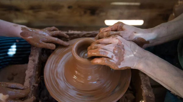 The Potter teaches the child to work on the Potters wheel. Hands of people in close-up. Working with clay, handmade.