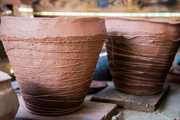 I keramikaffären faller solstrålarna på keramiken. En lerkruka och en kanna. Det naturliga mönstret på leran. Bakgrund, struktur. — Stockfoto