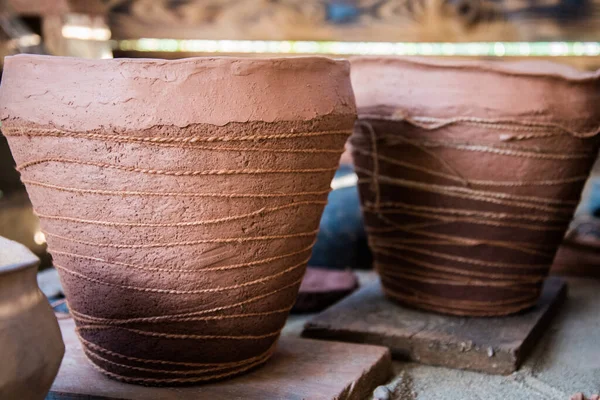 En la tienda de cerámica, los rayos del sol caen sobre la cerámica. Una olla de barro y una jarra. El patrón natural en la arcilla. Fondo, textura. — Foto de Stock