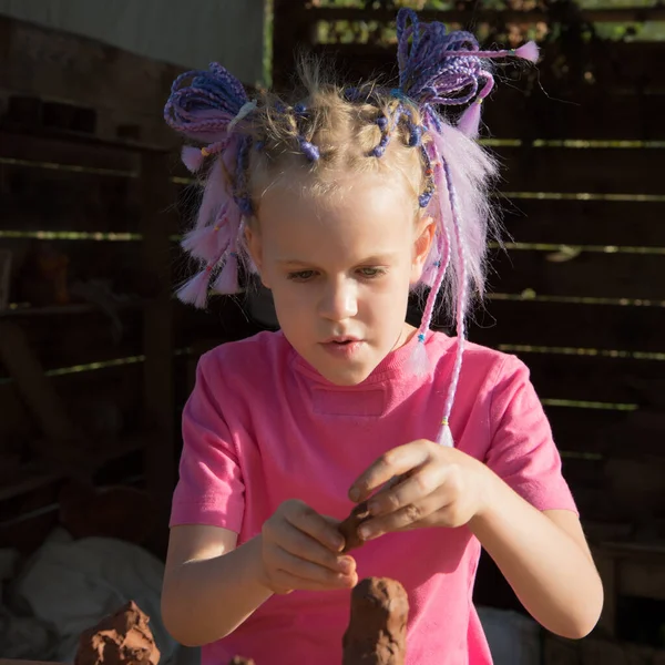 Dívka s krásným účesem vymodeluje výrobek z hlíny. Koncept výuky, manuální práce. — Stock fotografie