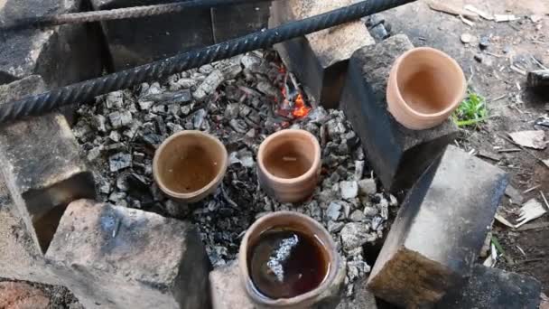 Le tazze di terracotta stanno vicino alle braci ardenti del fuoco. Tè caldo profumato. Escursioni nella natura. Rilassante e godersi il tè nella natura. — Video Stock
