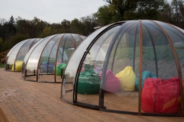 Ahşap bir terasta şeffaf bir Igloo. Farklı şirketler için izole edilmiş bir yer. Koronavirüsten korunma.