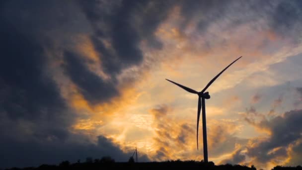 Una sola turbina eólica gira en torno a la producción de energía con un fondo de cielo amarillo oscuro . — Vídeo de stock