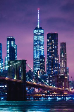 Manzarası şehir New York'un Brooklyn Köprüsü ve gökdelenler Doğu Brooklyn sunset görünümden sonra alacakaranlıkta ışıklarla aydınlatılmış Nehri üzerinde