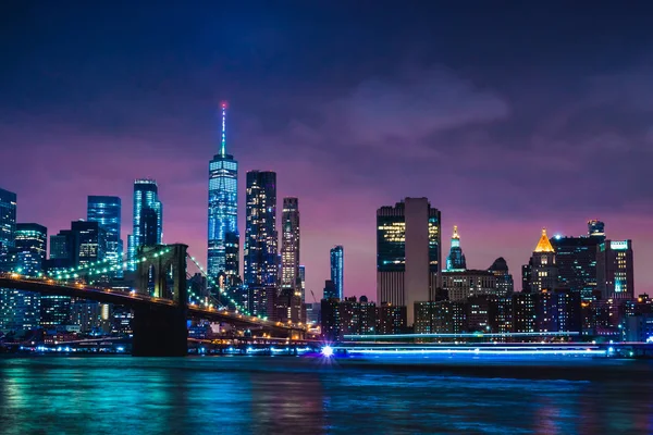 Manzarası şehir New York'un Brooklyn Köprüsü ve gökdelenler Doğu Brooklyn sunset görünümden sonra alacakaranlıkta ışıklarla aydınlatılmış Nehri üzerinde