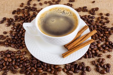 Bir fincan sıcak americano ve tarçınlı beyaz fincan. Çuval bezelyeli kahve. Kahve yapma konsepti. Düz yatış, üst manzara, minimalizm.