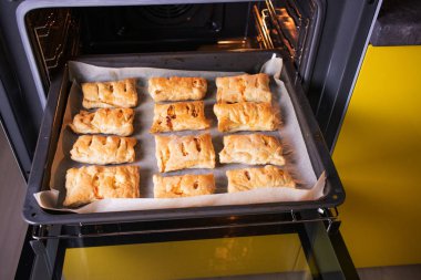 Fırında pişmiş çörekler pişiyor. Ev yapımı, yemek pişirme konsepti. Uzayı kopyala Sıcak renkler.