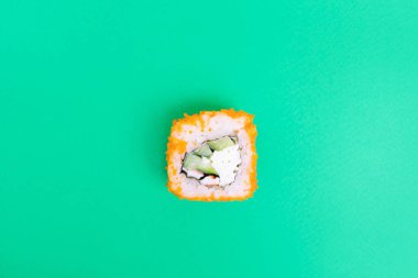 Parlak yeşil arka planda tobiko havyarı, salatalık ve yengeç etiyle yuvarlan. Minimalist stil Japon yemeği konsepti. Düz yerde, üst tarafta. Boşluğu kopyala.