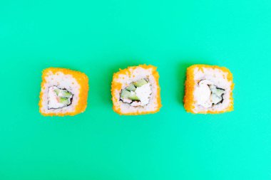 Parlak yeşil arka planda tobiko havyarı, salatalık ve yengeç eti. Minimalist stil Japon yemeği konsepti. Düz yerde, üst tarafta. Boşluğu kopyala.