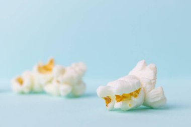 Pastel mavi arka planda yakın plan patlamış mısır. Sağlıksız diyet konsepti. Minimalizm, düz yatış, üst görünüm, metin için yer.