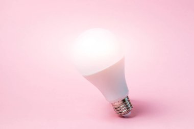 Öncü ampul, pastel pembe arka planda duruyor. Lambadan gelen ışık. Fikir kavramı. Minimalizm, metin için yer.