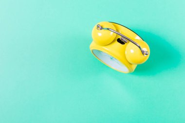 Çalar saat yeşil arka planda, üst manzara düz yerde. Sabah küfü konsepti. Arkaplan görüntüsü, minimalizm. Boşluğu kopyala.