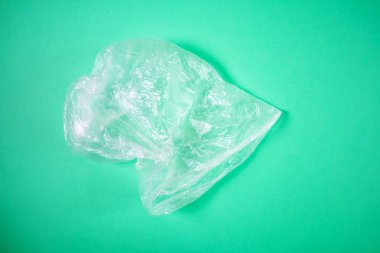 Selofan şeffaf çanta parlak yeşil bir arka planda yatıyor. Minimalist resim arkaplan olarak uygundur, metin veya logo için bir yer vardır. Üst görünüm