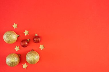 Yeni yıl düzlüğü. Parlak kırmızı noel baloları ve parlak kırmızı şenlik arka planında yıldızlar. Üst görünüm, telif alanı, minimalizm.