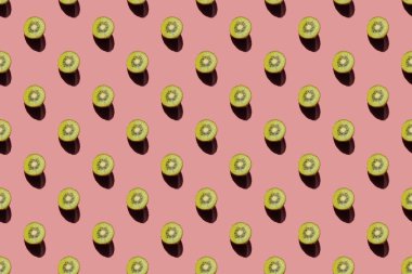 Pastel pembe arka planda olgun sulu kivi parçaları. Yaz ışığı pozitif konsept. Yaratıcı desen, minimalizm, üst görüş, düz yatak. Lezzetli ve sağlıklı yemekler.. 