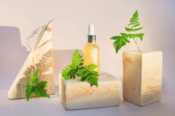 Cosmetic natural oil in a transparent bottle, wooden square and triangular shape. Wood, vegetation and oil. The concept of organic cosmetics, bio, eco, zero waste. Skin Care, Aromatherapy.