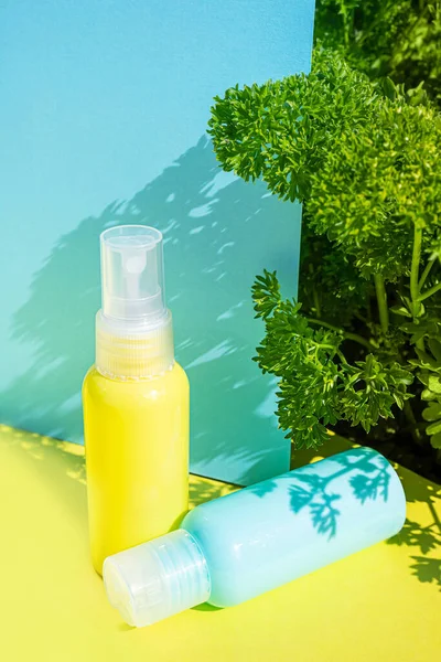 黄色和蓝色的化妆品瓶 底色相同 侧面是新鲜的香草 有机精华 自然美和保健产品的时尚概念 — 图库照片