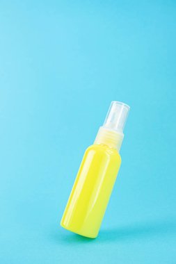 Mavi arka planda sarı kozmetik şişe. Organik esansların, güzelliğin ve sağlık ürünlerinin şık bir konsepti. Boşluğu, minimalizmi, havalanma etkisini kopyala.